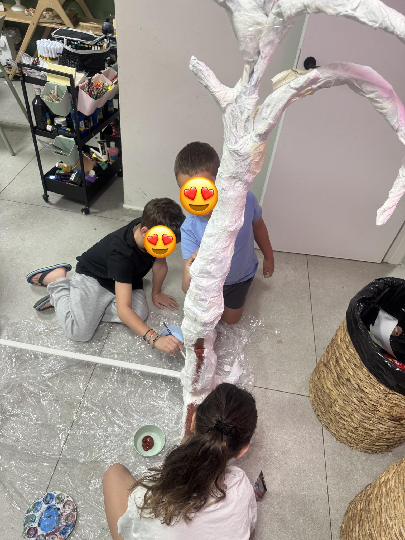 שלושה ילדים בונים יחד פסל עץ גדול מנייר — פעילות יצירה קבוצתית בסטודיו ArtyParty